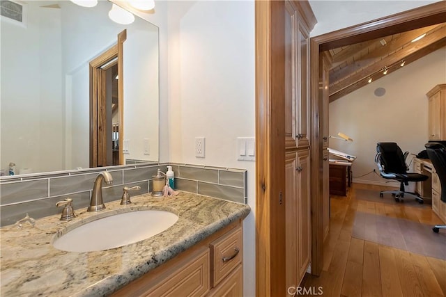 bathroom featuring beamed ceiling, vanity, and wood-type flooring