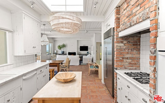 kitchen featuring pendant lighting, stainless steel appliances, light tile floors, tasteful backsplash, and white cabinetry