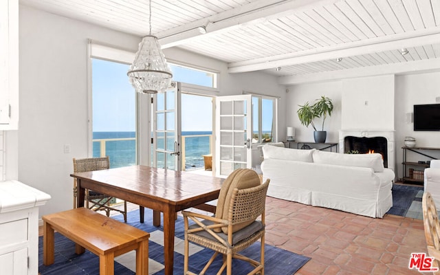 tiled dining space with a chandelier, a water view, french doors, and beam ceiling