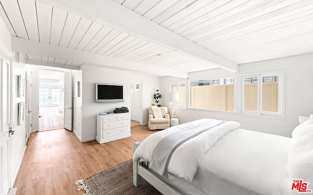 bedroom with beam ceiling and light hardwood / wood-style floors