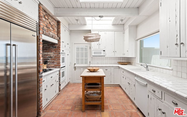 kitchen featuring white cabinets, tasteful backsplash, stainless steel appliances, and beam ceiling