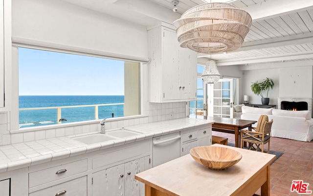 kitchen with white cabinets, backsplash, tile countertops, dishwasher, and sink