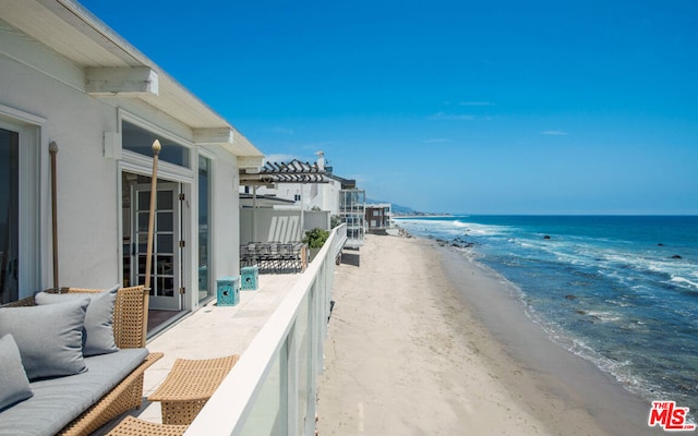 balcony with a view of the beach, a pergola, and a water view