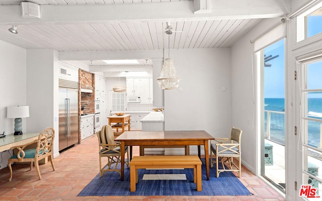 dining area featuring a water view and beamed ceiling