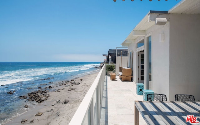 balcony featuring a view of the beach and a water view