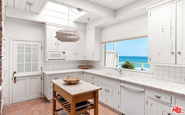 kitchen featuring beam ceiling, tasteful backsplash, white appliances, and white cabinets