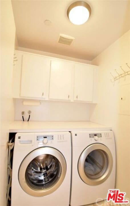 washroom with cabinets and washing machine and dryer