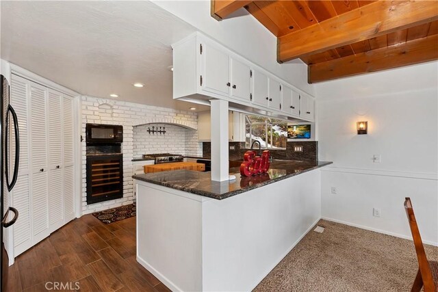 kitchen with kitchen peninsula, stainless steel appliances, beam ceiling, white cabinets, and wine cooler