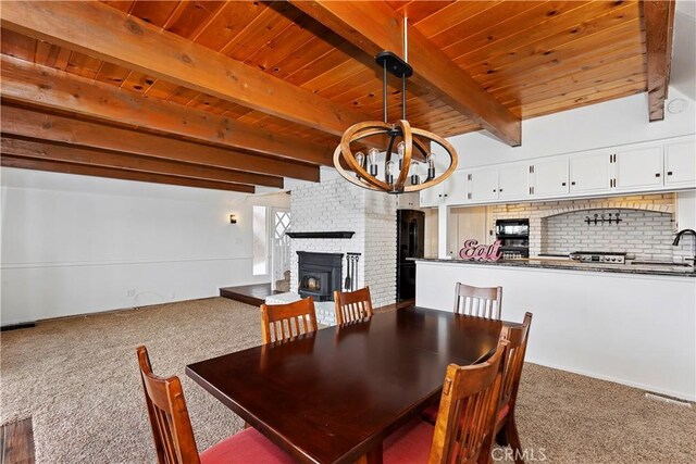 dining space featuring beamed ceiling, carpet flooring, a chandelier, and wooden ceiling