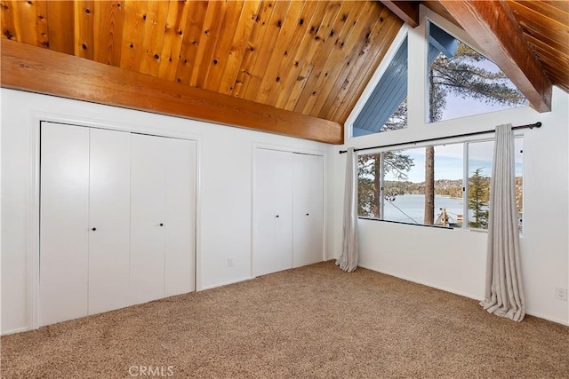 unfurnished bedroom featuring carpet, beamed ceiling, a water view, and two closets