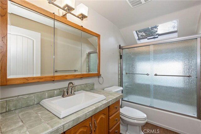 full bathroom with combined bath / shower with glass door, vanity, vaulted ceiling, wood-type flooring, and toilet