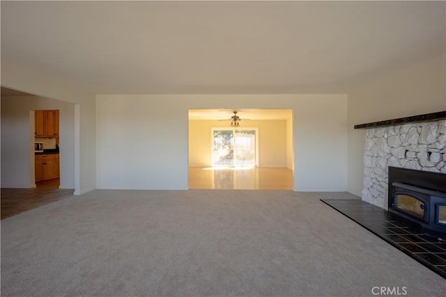 unfurnished living room featuring dark carpet and a wood stove