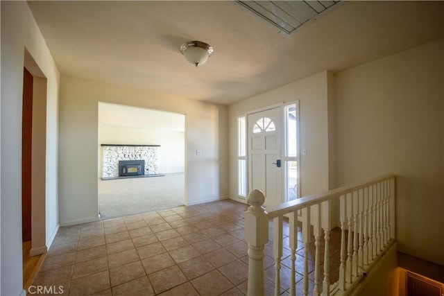 tiled foyer featuring a stone fireplace