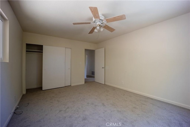 unfurnished bedroom featuring a closet, light colored carpet, and ceiling fan