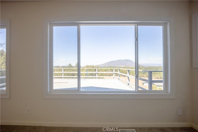 unfurnished room featuring a mountain view, plenty of natural light, and carpet floors