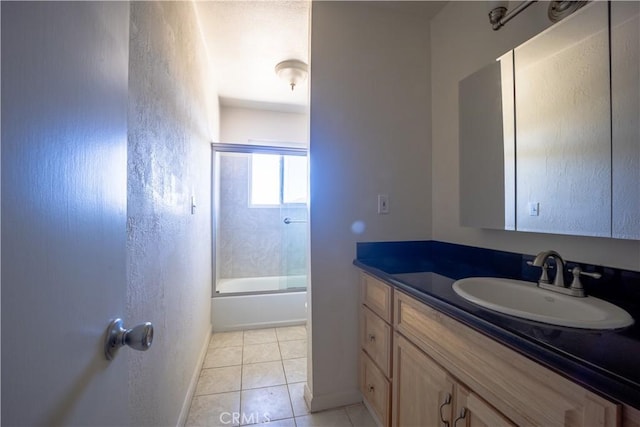 bathroom with tile patterned flooring, vanity, and combined bath / shower with glass door