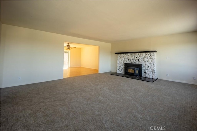 unfurnished living room featuring carpet flooring, ceiling fan, and a wood stove