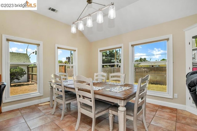 tiled dining room with a chandelier and vaulted ceiling