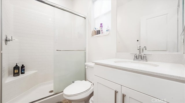 bathroom featuring toilet, a shower with shower door, and large vanity