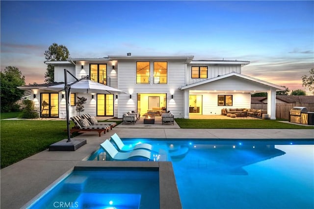 back house at dusk featuring outdoor lounge area, a patio area, a yard, and a fenced in pool