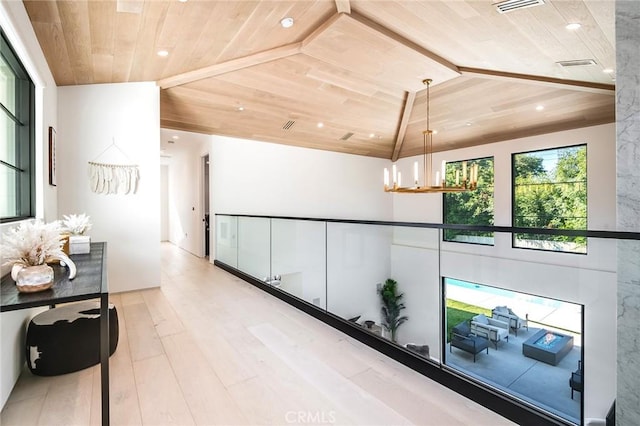 corridor featuring lofted ceiling, light hardwood / wood-style floors, wood ceiling, and a chandelier