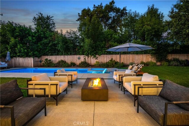 pool at dusk with an outdoor living space with a fire pit and a patio area