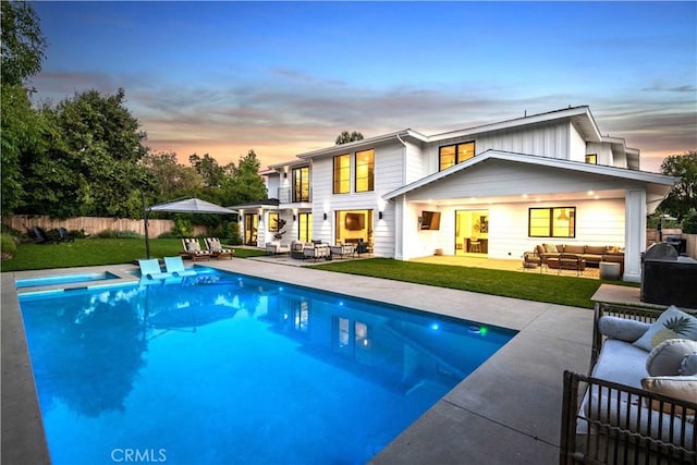 back house at dusk featuring an outdoor living space, a patio, and a pool with hot tub