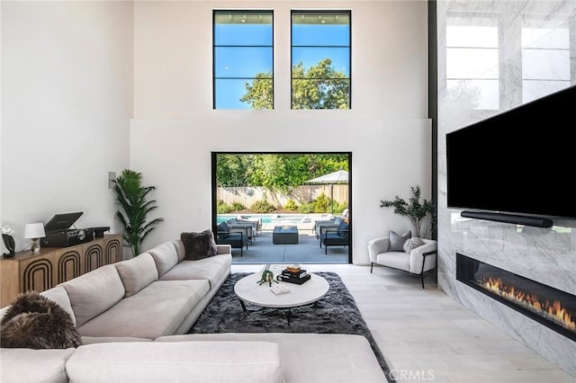 living room with a high end fireplace, light wood-type flooring, and plenty of natural light