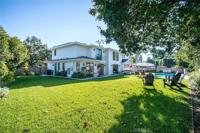 rear view of property featuring a yard and central AC