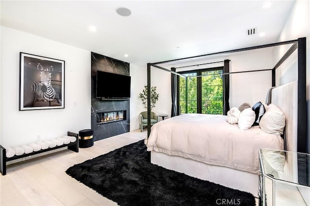 bedroom with light hardwood / wood-style floors and a fireplace