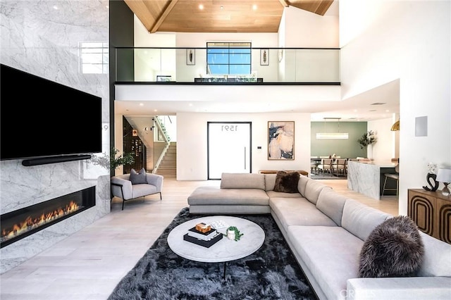 living room with a premium fireplace, wooden ceiling, and a high ceiling