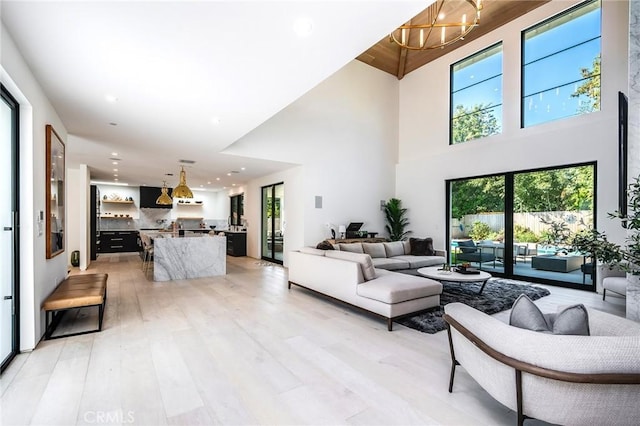 living room featuring a high ceiling, light hardwood / wood-style floors, and an inviting chandelier