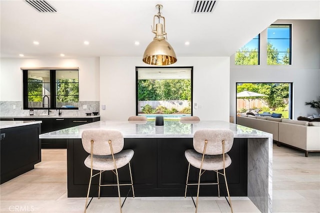 kitchen with a kitchen island, light stone counters, a breakfast bar area, and tasteful backsplash