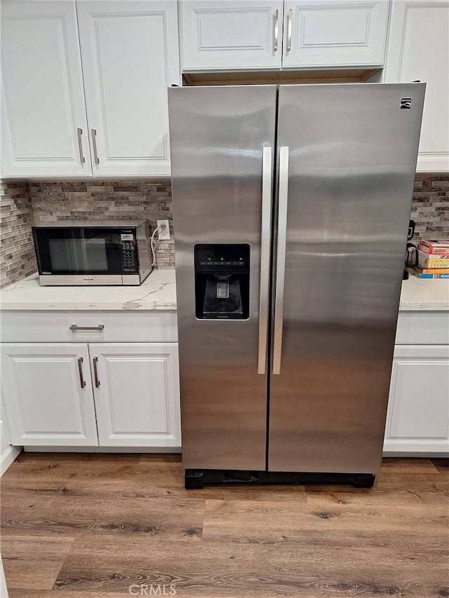 kitchen featuring stainless steel fridge with ice dispenser, decorative backsplash, white cabinets, and light wood-type flooring