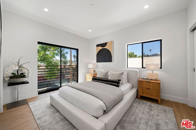 bedroom with light hardwood / wood-style floors, access to outside, and multiple windows