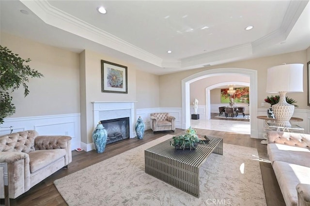 living room featuring a raised ceiling, a fireplace, dark hardwood / wood-style floors, and ornamental molding