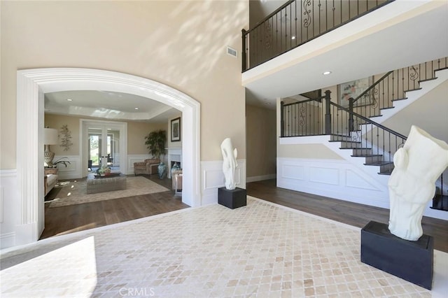 entrance foyer featuring wood-type flooring, a towering ceiling, a raised ceiling, and french doors