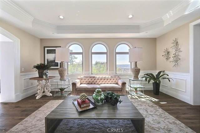 living room featuring dark hardwood / wood-style flooring, crown molding, and a tray ceiling