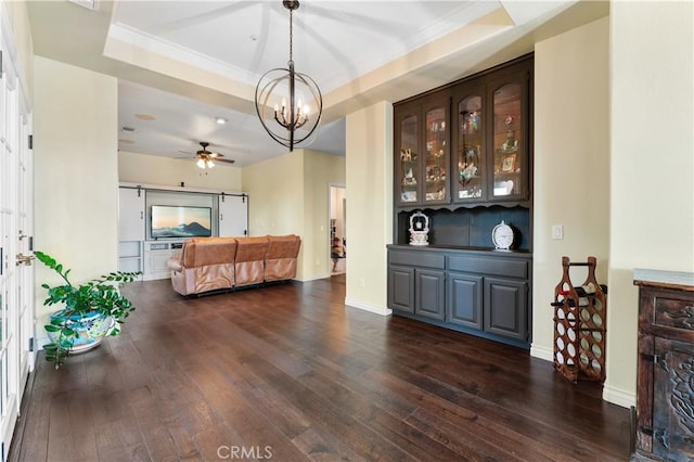 living room with dark hardwood / wood-style floors, crown molding, ceiling fan with notable chandelier, and a tray ceiling