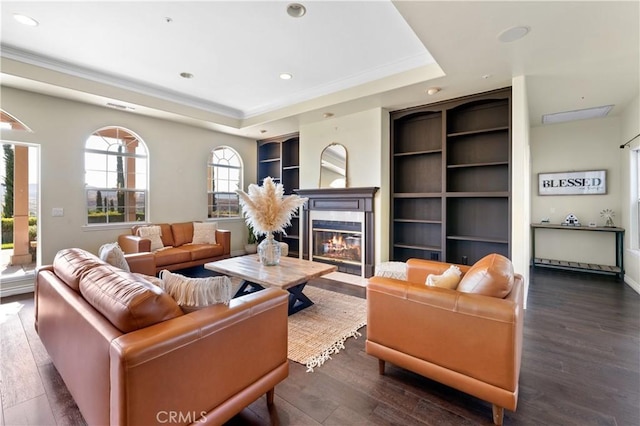 living room featuring built in features, a raised ceiling, and dark wood-type flooring