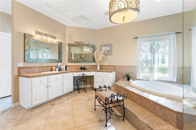 bathroom featuring tile patterned flooring, vanity, and a relaxing tiled tub