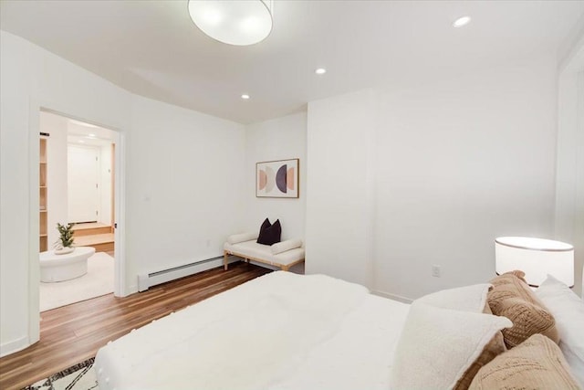 bedroom with a baseboard heating unit, connected bathroom, and light hardwood / wood-style flooring