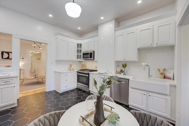 kitchen featuring pendant lighting, white cabinets, appliances with stainless steel finishes, sink, and backsplash