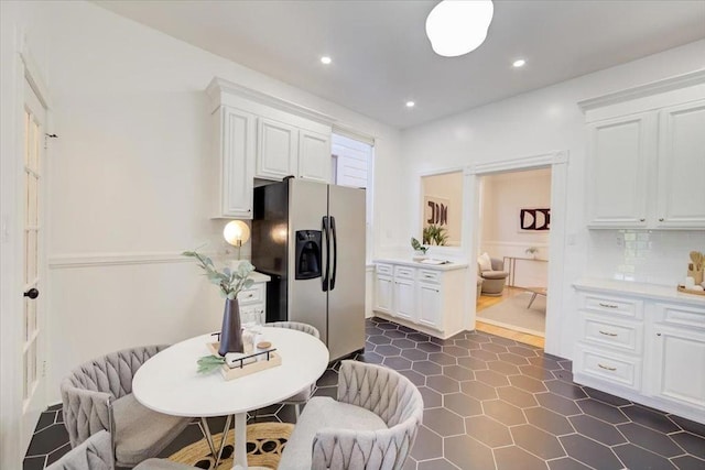 kitchen featuring white cabinetry, backsplash, and stainless steel fridge