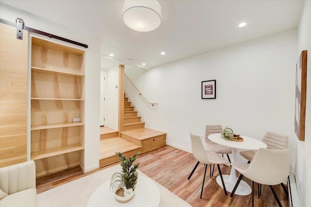 dining room with a barn door, built in features, and hardwood / wood-style floors