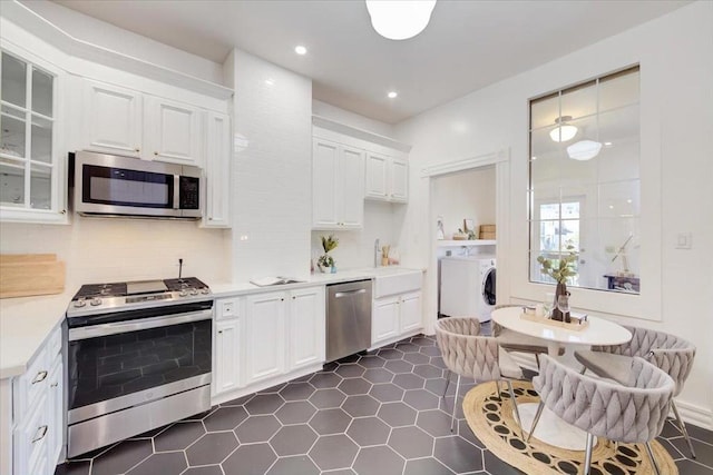 kitchen with decorative backsplash, white cabinets, and stainless steel appliances