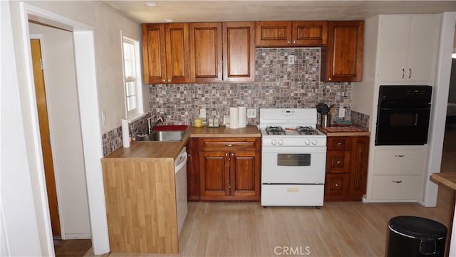 kitchen with tasteful backsplash, sink, white appliances, and light hardwood / wood-style floors