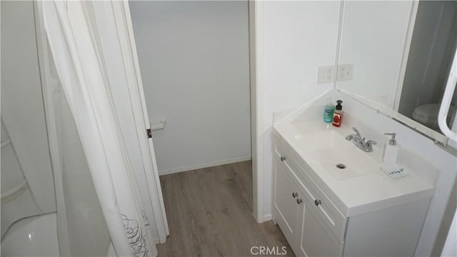 bathroom with toilet, vanity, and hardwood / wood-style flooring