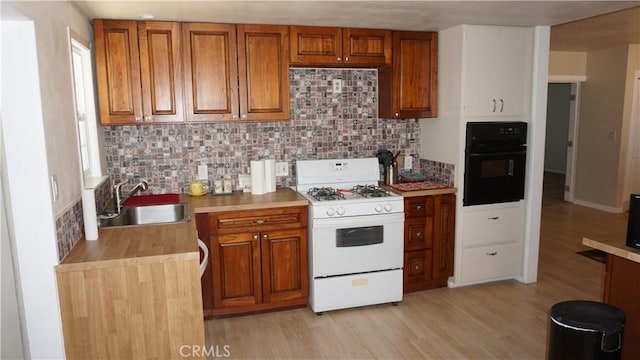 kitchen featuring white range with gas cooktop, decorative backsplash, black oven, and sink