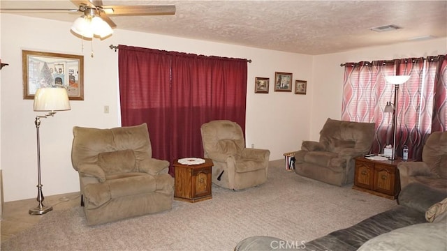 carpeted living room with ceiling fan and a textured ceiling